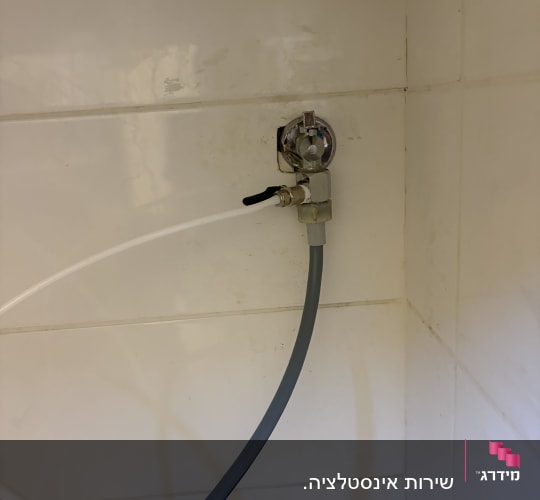 ברז וצינורות במטבח על קיר לבן
